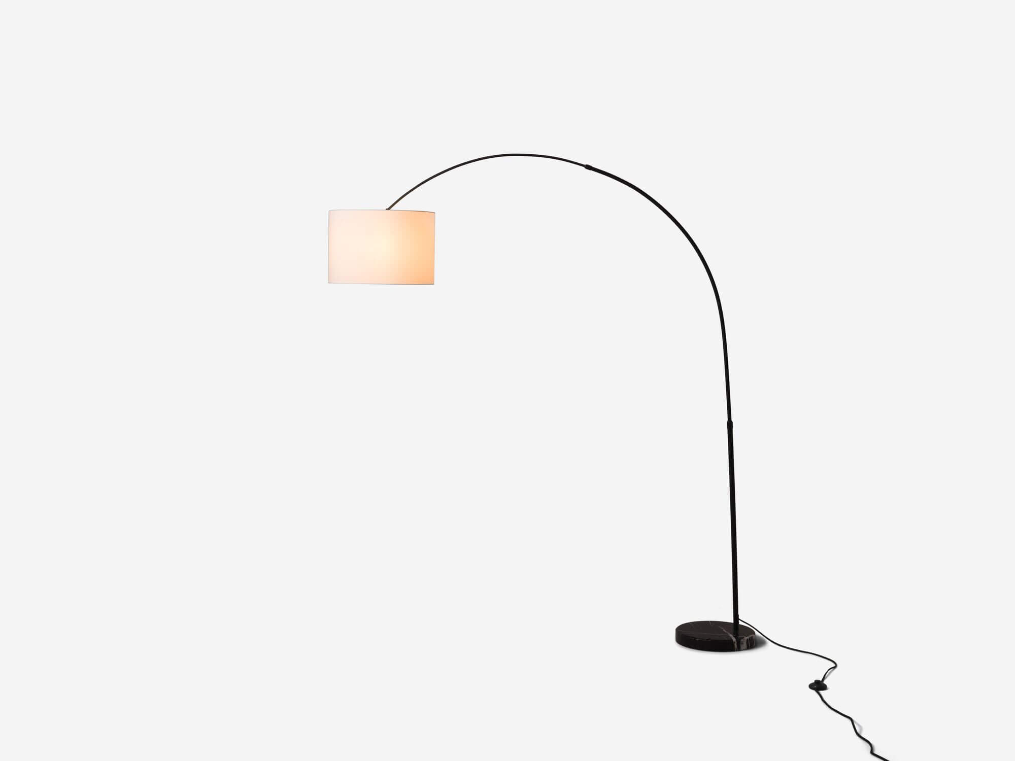 Side view of white arc floor lamp with light on